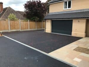 Asphalt driveway with red chippings outside a double garage