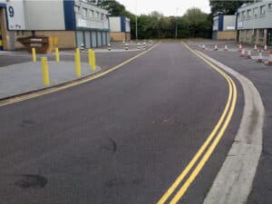 Resurfaced access road with double yellow lines at an industrial site