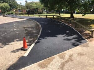 Newly laid tarmac footpath with a traffic cone