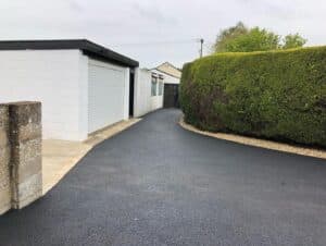 Tarmac drive beside a garage and hedge